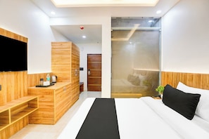 A modern hotel room with a bed, bedside table, and a TV mounted on the wall.