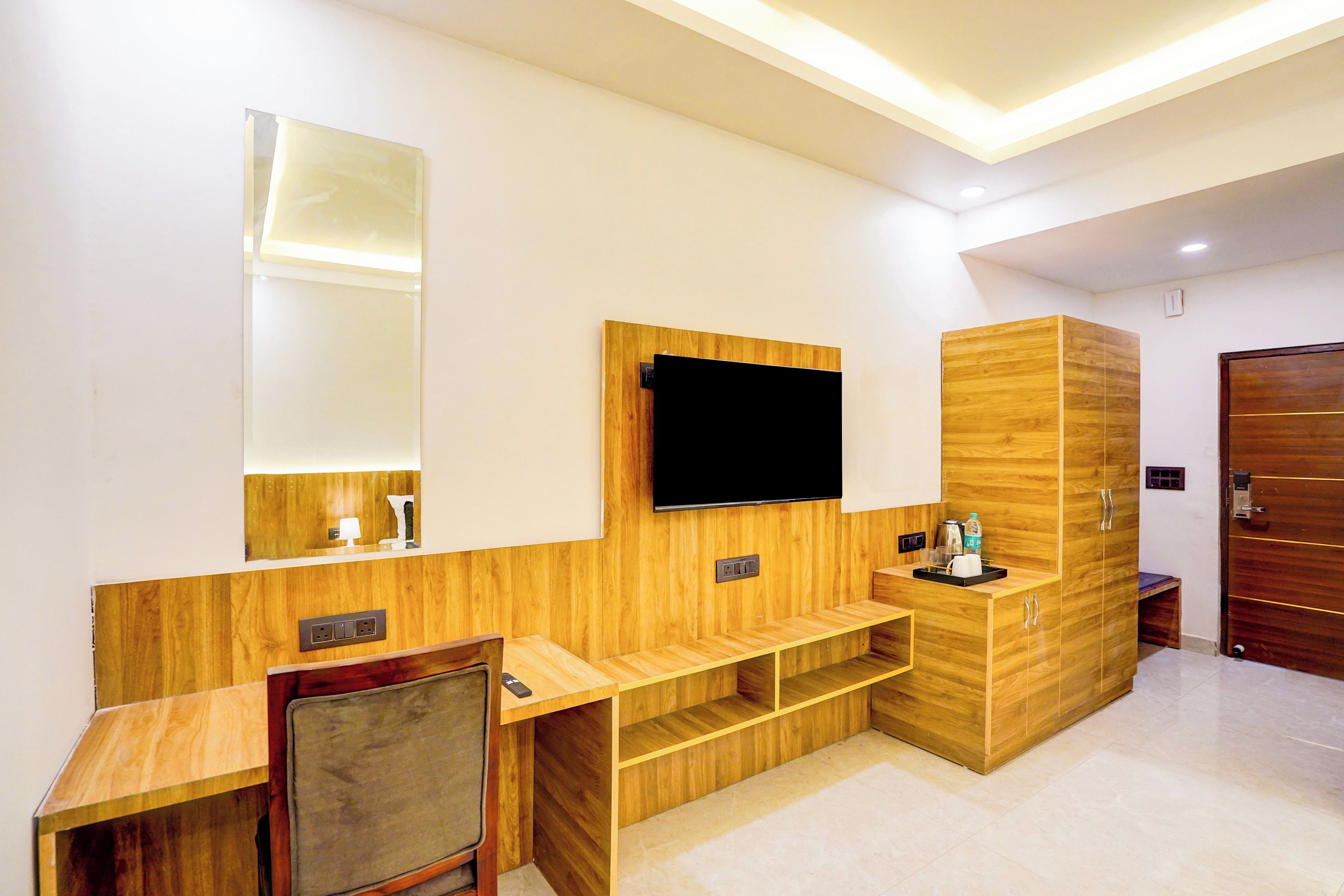 Un baño moderno con tocador de madera, un espejo, un televisor montado en la pared y un gabinete de madera con lavamanos.