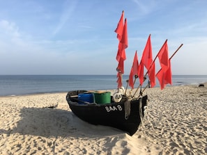 A boat with red flags on a sandy beach. - Villa Poseidon 18 (Binz)