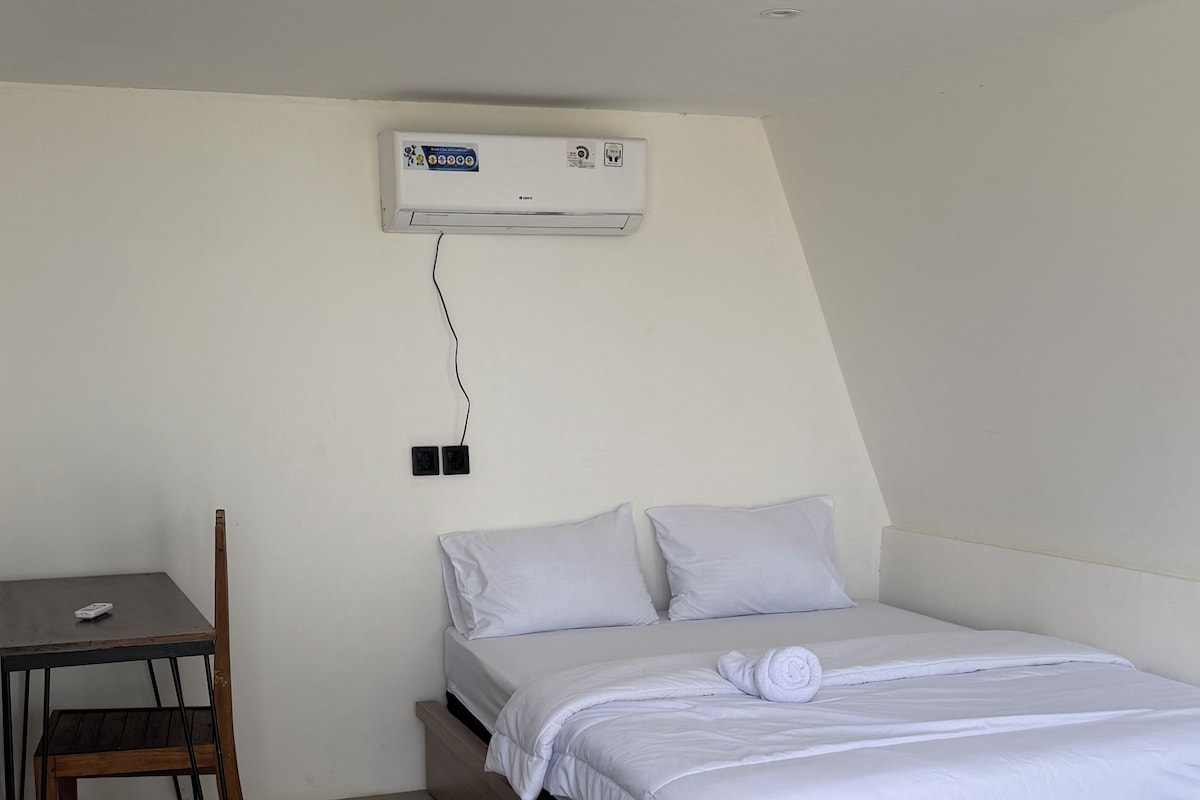 A bedroom with a bed, a chair, and a wall-mounted air conditioner.