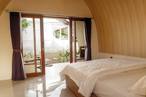 A bedroom with a large bed, a sliding glass door leading to an outdoor area, and a wooden ceiling. - Windy Senaru (Bayan)