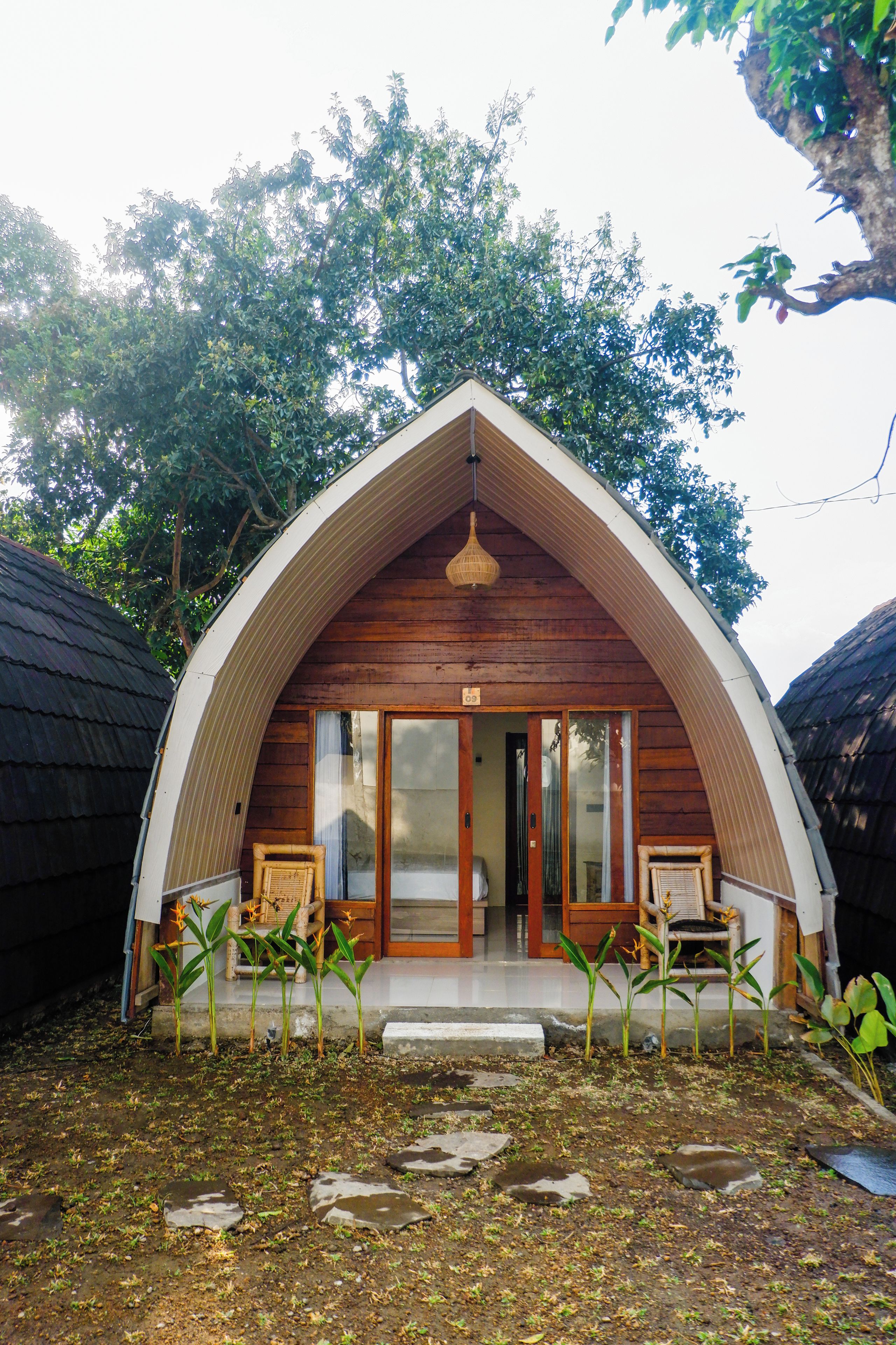 Una pequeña estructura de madera tipo cabaña con un porche y una sola puerta.