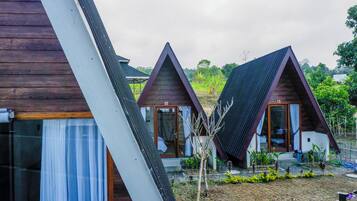 A row of triangular-roofed cabins with large windows and a garden area in front.