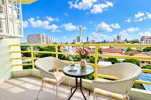 A balcony with wicker chairs, a small table, and a vase with flowers. - Your Coastal Getaway Just Minutes From Jomtien Beach (Pattaya)