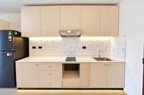 A modern kitchen with light wood cabinets, a stainless steel refrigerator, a built-in oven, and a marble backsplash. - Your Coastal Getaway Just Minutes From Jomtien Beach (Pattaya)
