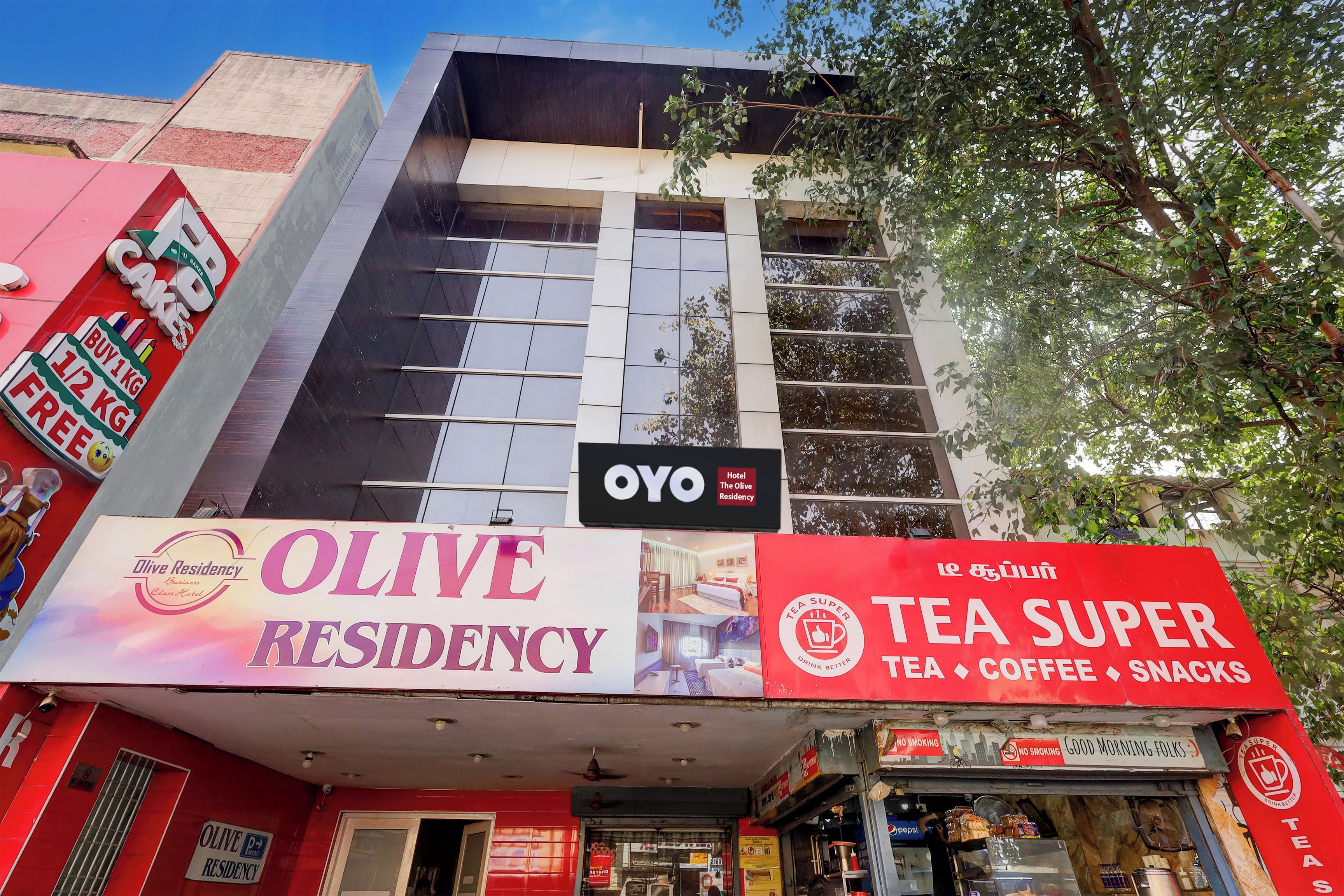 A building with signage for 'Olive Residency' and 'Tea Super' indicating a hotel and a tea shop.