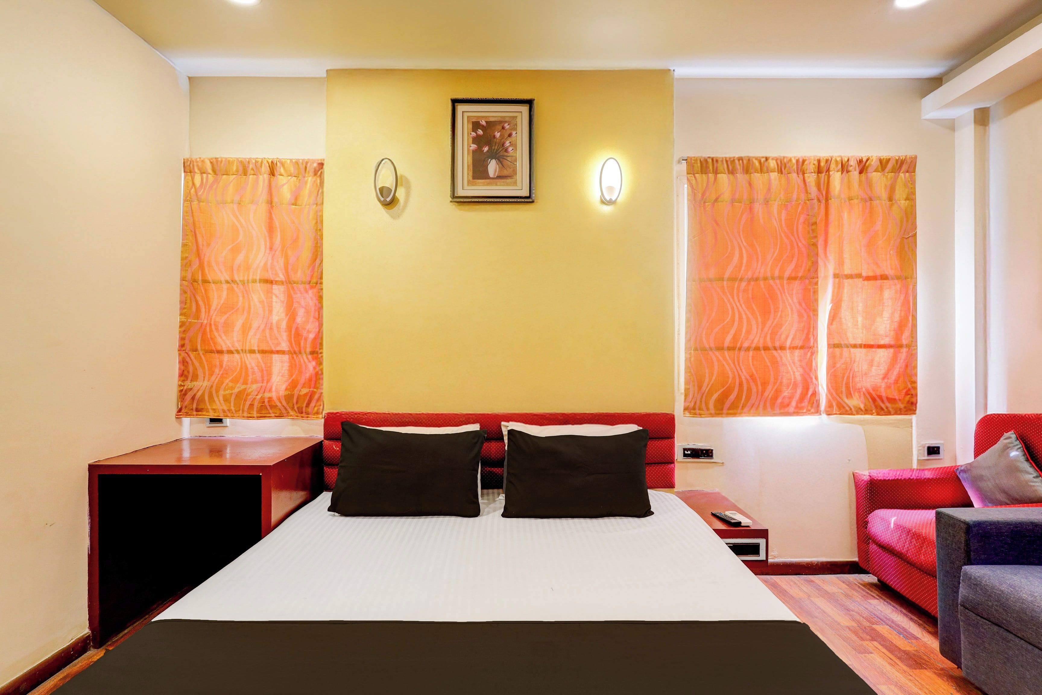 A hotel room with a bed, a desk, a chair, and a sofa.