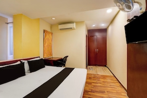 A hotel room with a bed, a desk, an air conditioning unit, a wardrobe, and a television. - Hotel O  The Olive Residency  (Chennai)