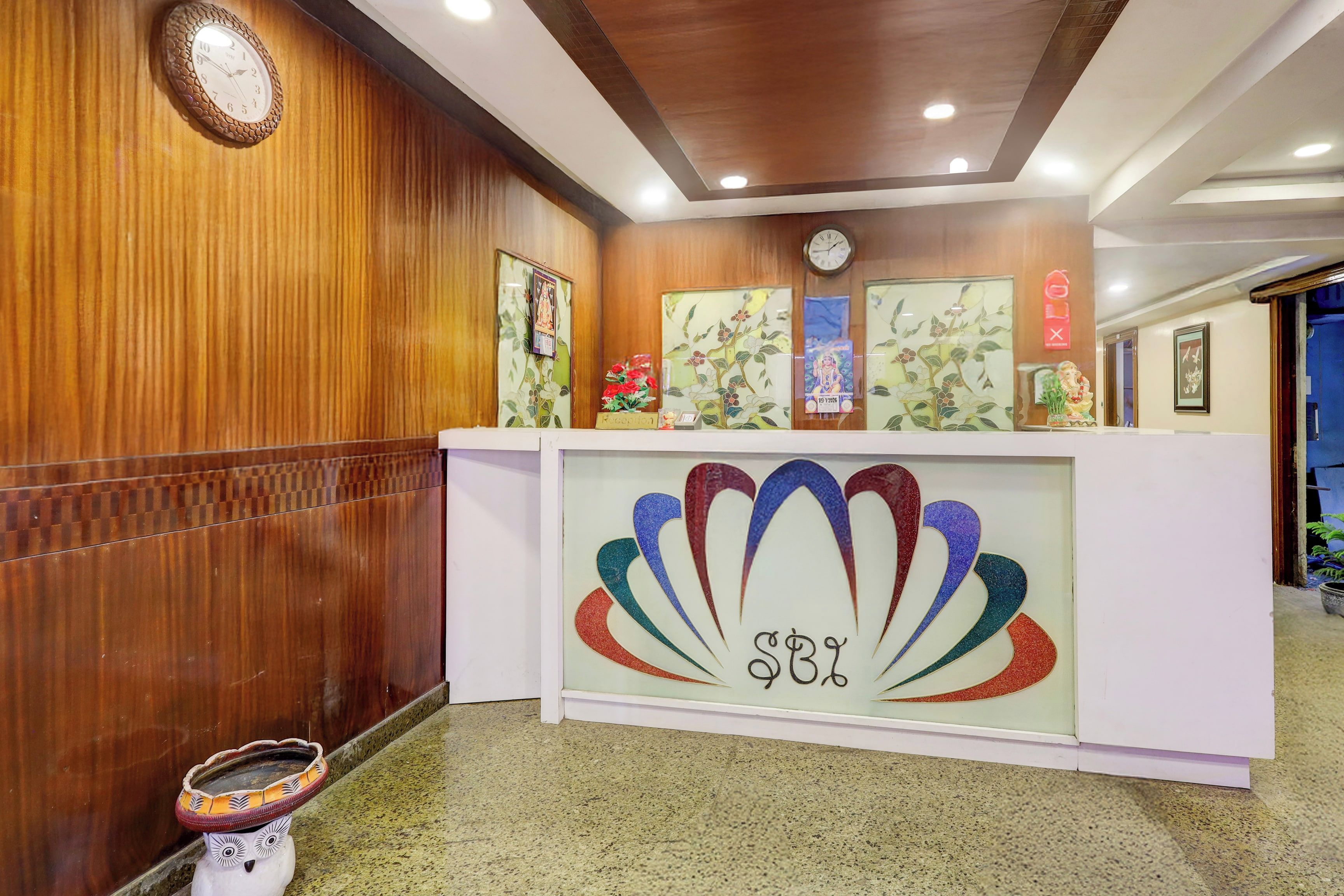A reception desk with a clock, framed artwork, and a decorative emblem.