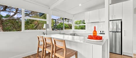 Una cocina moderna con armarios blancos, un refrigerador de acero inoxidable y una isla grande con taburetes de bar.