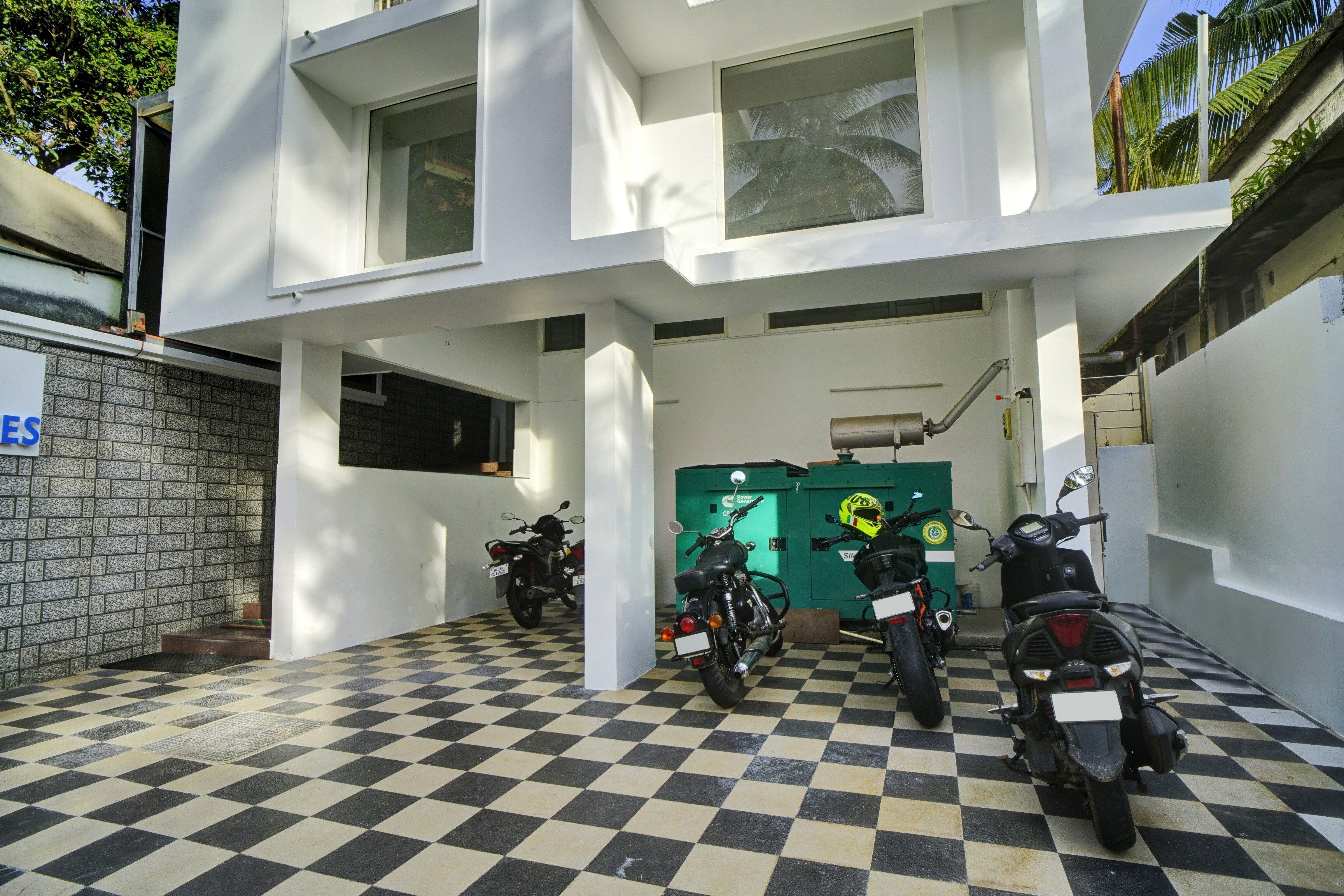 Un edificio con piso a cuadros, un cuarto de servicio verde y motocicletas estacionadas.