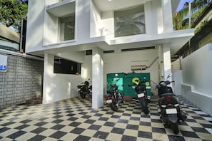 A building with a checkered floor, a green utility room, and parked motorcycles. - Hotel O Crystal Executive Suites (Kanayannur)