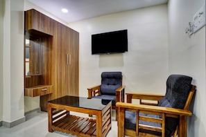 Una sala de estar con un aparador de madera, un televisor de pantalla plana y dos sillones.