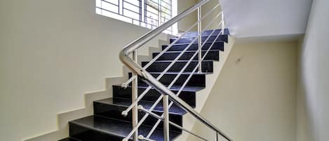 Una escalera con barandilla metálica y peldaños negros.