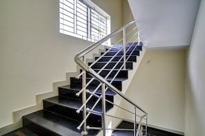 Una escalera con barandilla metálica y peldaños negros.