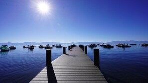 Une jetée en bois mène à une étendue d’eau calme, où des bateaux sont amarrés de part et d’autre.