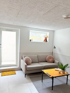 Un salon avec un canapé, une table basse, une plante en pot et une fenêtre donnant sur un beau paysage.