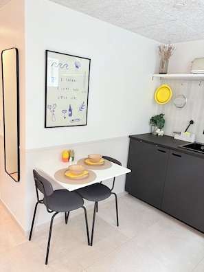 Une cuisine moderne avec une table blanche, deux chaises et une citation encadrée accrochée au mur.
