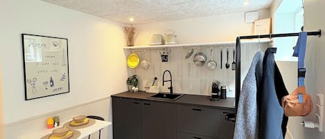 Eine kompakte Küche mit Essbereich, ausgestattet mit einer weißen Decke, einem Spülbecken und einem kleinen Esstisch mit Stühlen.