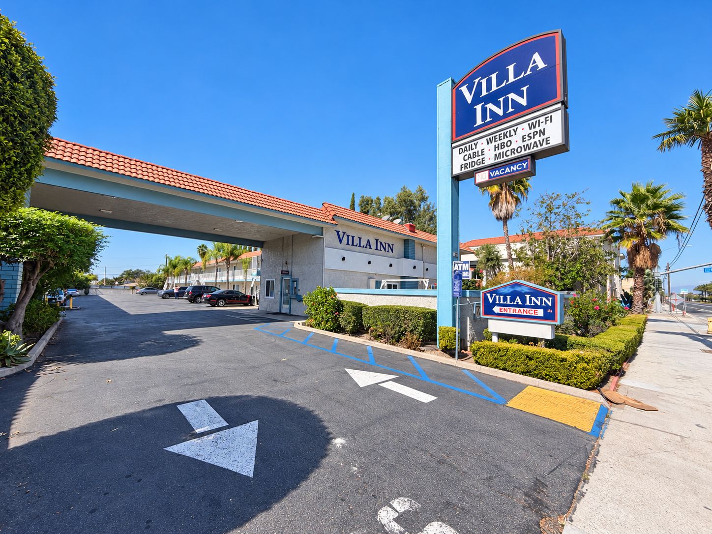A Villa Inn hotel with a clear sign, a parking lot with directional arrows, and a gas station in the background.