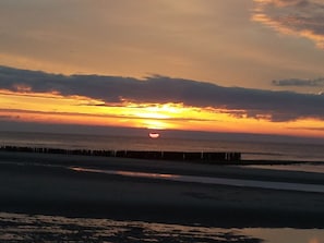 A sunset over a beach with a pier extending into the water. - Holiday Home With 1 Bedroom (Oostkapelle)