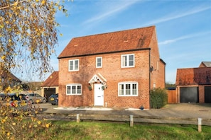 A two-story brick house with a garage, a front door, and a driveway. - The Hideaway - Luxury 4 Bedroom House in Bicester (Oxfordshire)