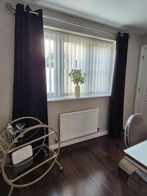 A room with a window, a radiator, a plant, a metal rack with glasses, and a chair. - The Hideaway - Luxury 4 Bedroom House in Bicester (Oxfordshire)