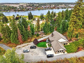 Un quartier résidentiel avec une maison dotée d’un garage, d’une allée où sont garées des voitures, et offrant une vue sur un lac où l’on peut apercevoir des bateaux.