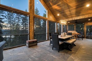 A spacious room with large windows, a dining area with a table and chairs, and a ceiling fan.