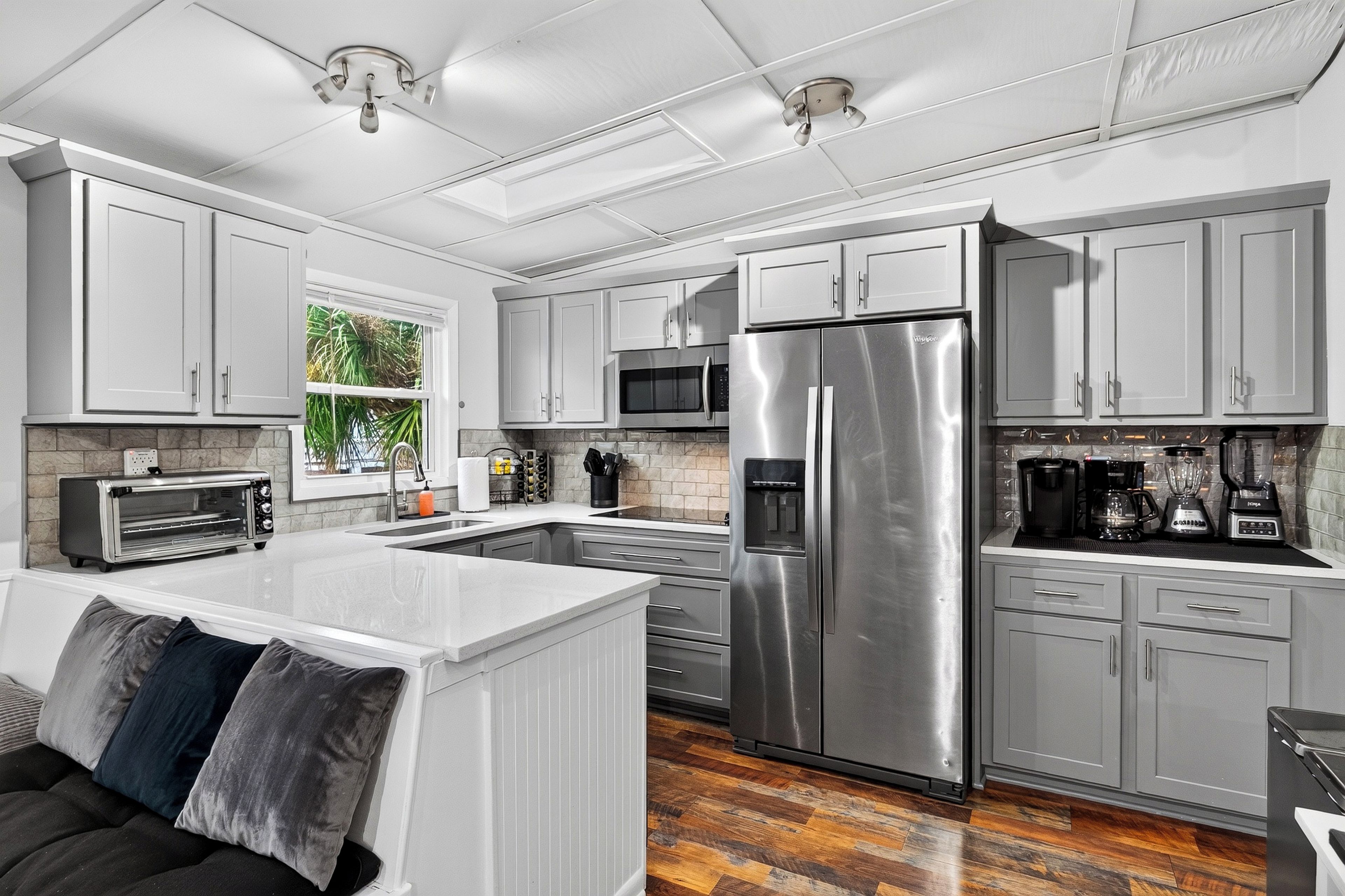 A modern kitchen with white cabinetry, stainless steel appliances, a built-in oven, and a central island with seating.