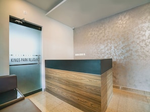 Un mostrador de recepción de diseño moderno, una pared con textura y un cartel que indica 'Kings Park Residence'.