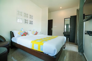 Una habitación de hotel con cama, una silla, armario y espejo.