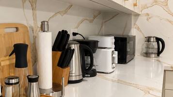 A modern kitchen with white marble countertops, stainless steel appliances, and gold handles on the cabinets.