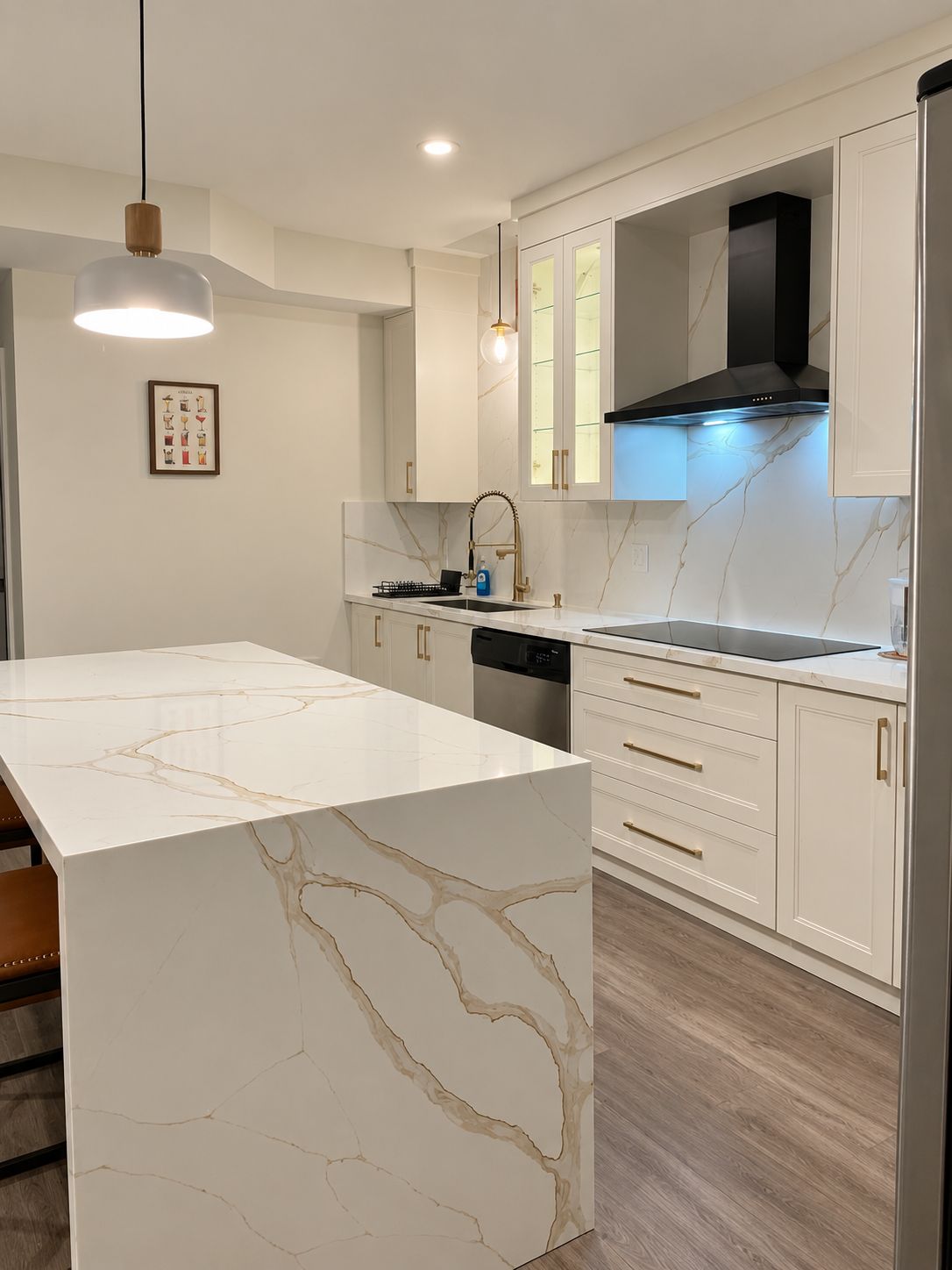 A modern kitchen with a marble island, white cabinetry, and a black range hood.