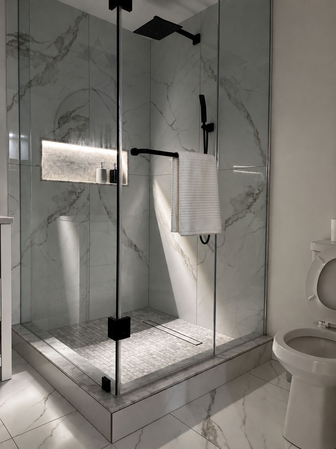 Ein modernes Badezimmer mit einer Glaskabine zur Dusche, einer Toilette und einem Waschbecken mit Marmorrückwand.