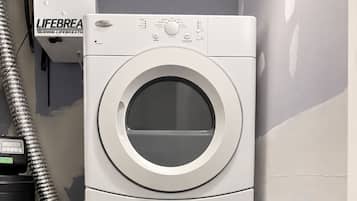 A stacked washer and dryer unit in a room with unfinished walls.