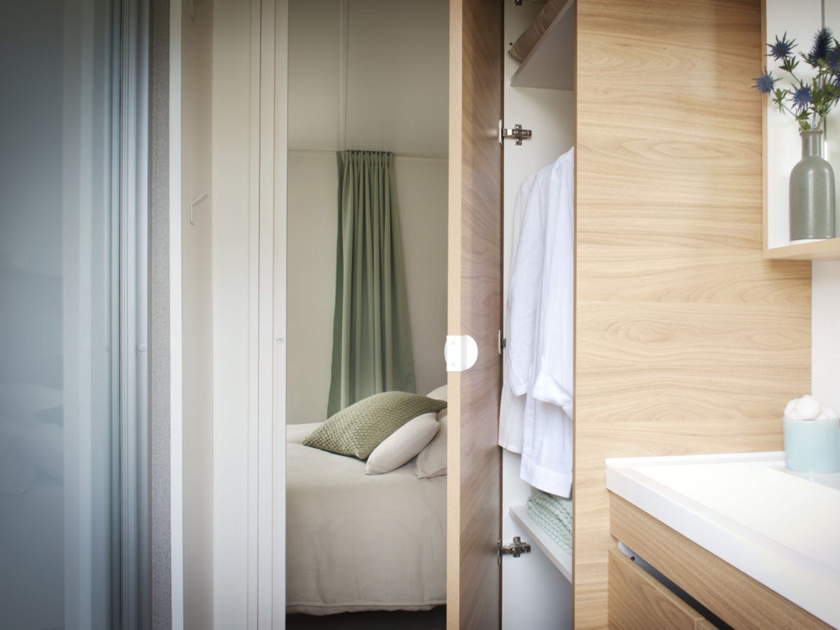 A bedroom with a bed, a green curtain, and a wooden wardrobe.