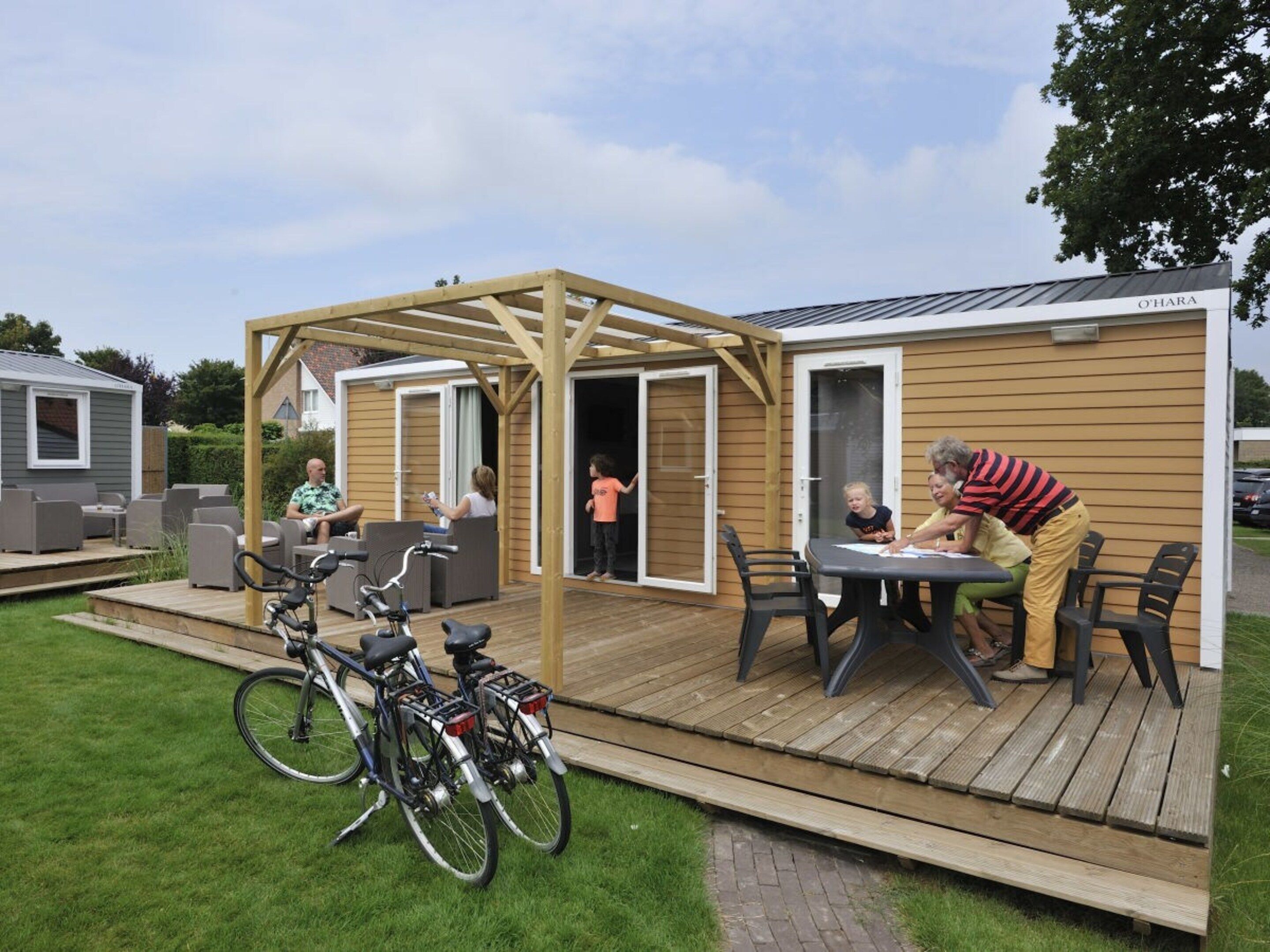 A wooden deck with outdoor seating, bicycles, and a covered area.