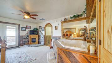 A bathroom with a wooden vanity, a bathtub, and a stone fireplace.