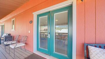 A covered porch with a teal door, a small seating area with chairs, and a sign indicating a room named 'Ponderosa Room'.