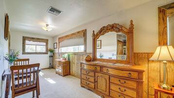 A room with a wooden dresser, a chair, a table, and a mirror.