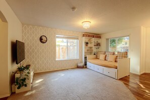 Ein Zimmer mit einem Bett, einem Fernseher, einem Fenster und einer Deckenleuchte.