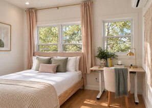 A bedroom with a bed, bedside table, lamp, and a view of trees through the window. - Spacious 3BR East Side Home, Near Brown & Miriam (Providence)