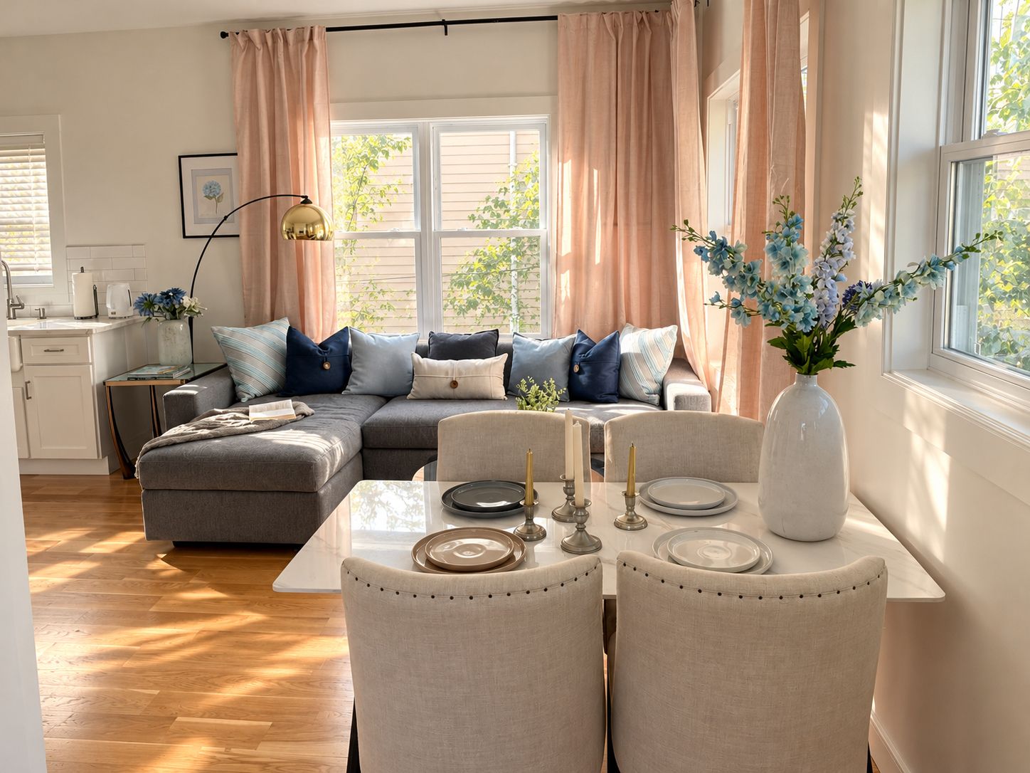 A modern living room with a sectional sofa, a dining table with chairs, and a vase with flowers.