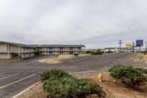 A large, empty parking lot with a building in the background. - 1 FULL BED | MOBILITY ACCESS RI SHWR, NSMK (Albuquerque)
