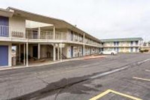 A multi-story motel with a flat facade, a covered front porch, and a parking lot in front. - Cozy Full Bed Smoking Room (Albuquerque)