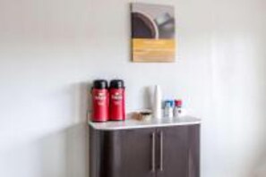 Un mini-bar contenant deux récipients rouges, une bouteille blanche et une petite bouteille, le tout posé sur un meuble sombre.