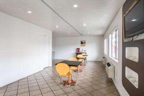Une salle de conférence dotée d’un sol carrelé de carreaux blancs, d’une porte blanche et d’une fenêtre offrant une vue dégagée.