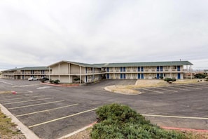 Ein Motel mit einem zentralen Parkplatz, mehreren Zimmern und einer kleinen Grünanlage.