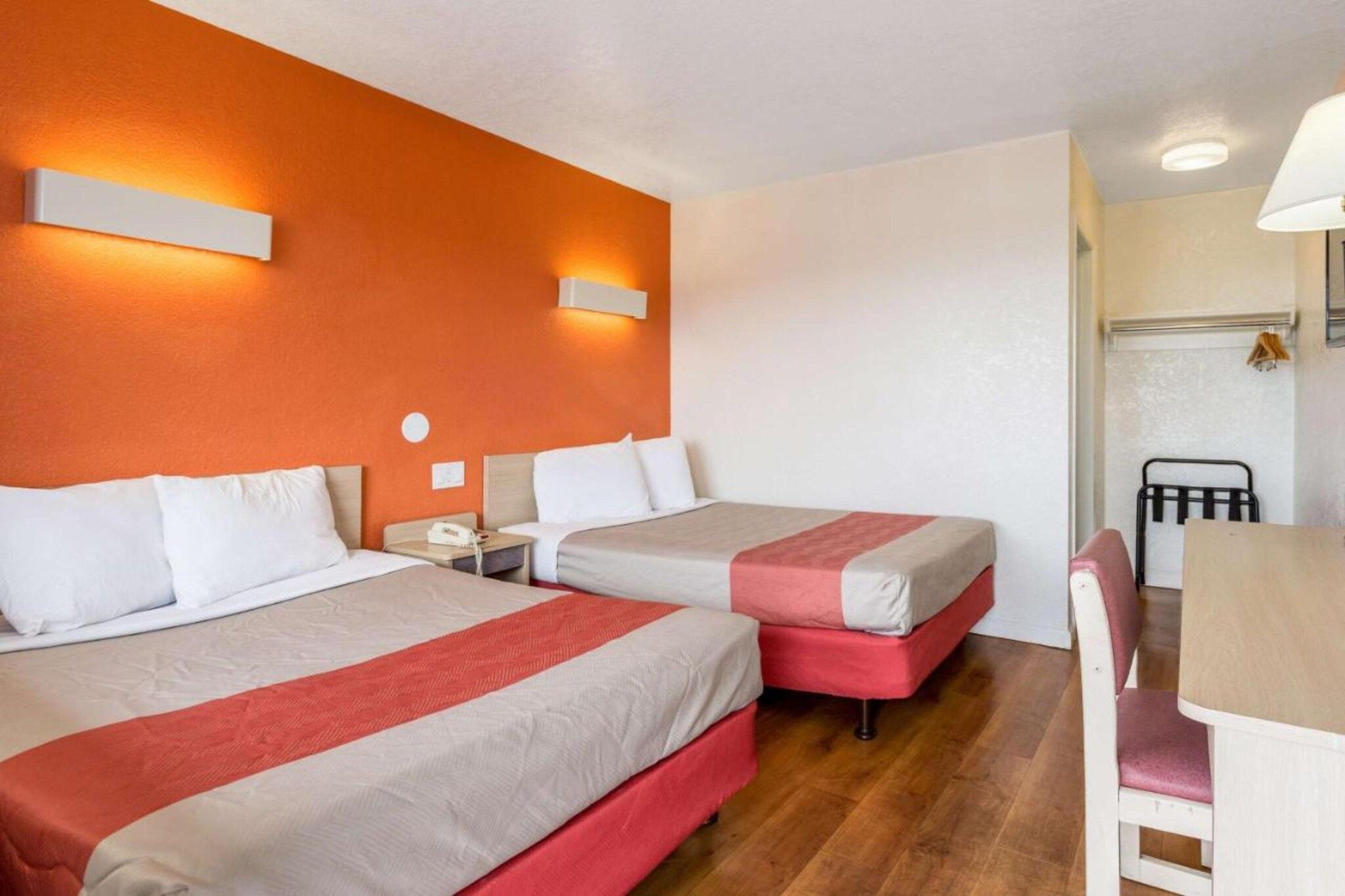 A hotel room with two beds, a desk, and a chair.